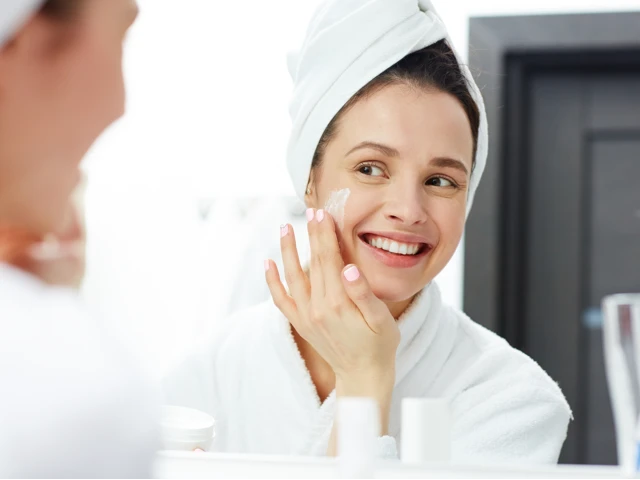 Białoskóra kobieta w białym ręczniku i szlafroku pielęgnująca skórę twarzy